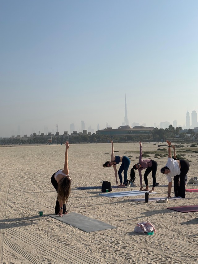 The Galentine's morning class folding forward, Burj Khalifa on the skyline behind