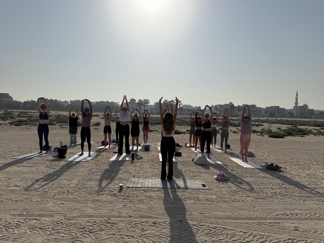 Sunrise beach Pilates class at Kite Beach reaching overhead as the sun comes up