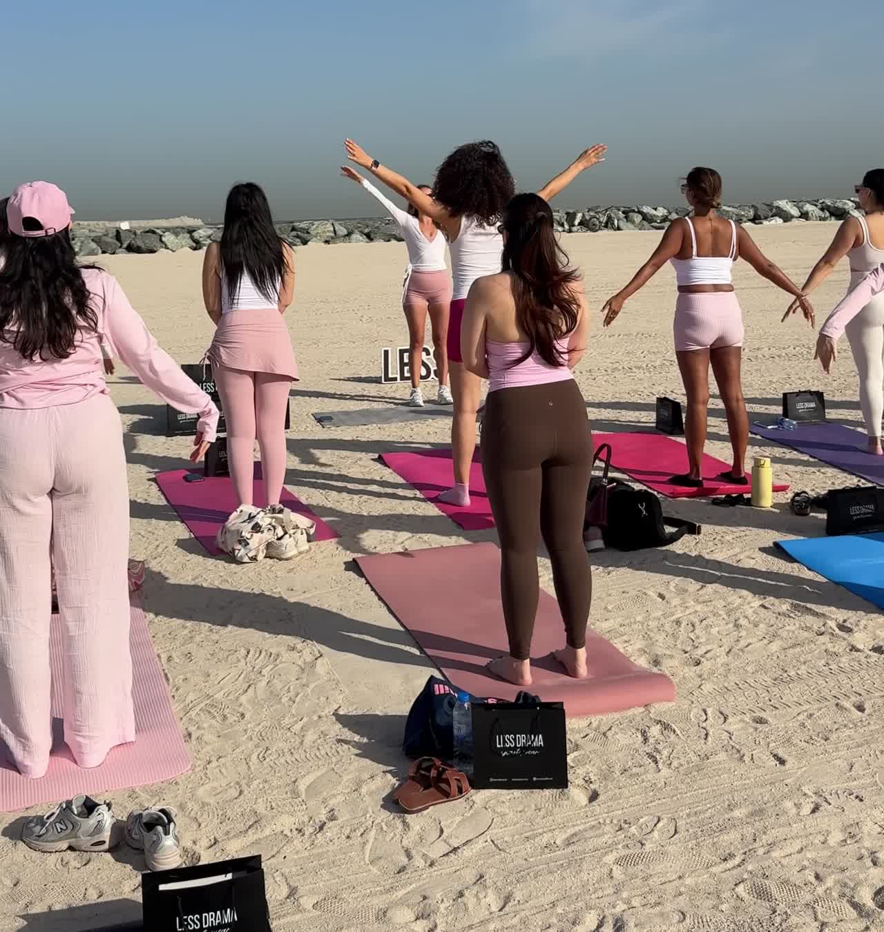A full Beach Pilates Dubai class stretching in unison on the sand at Kite Beach